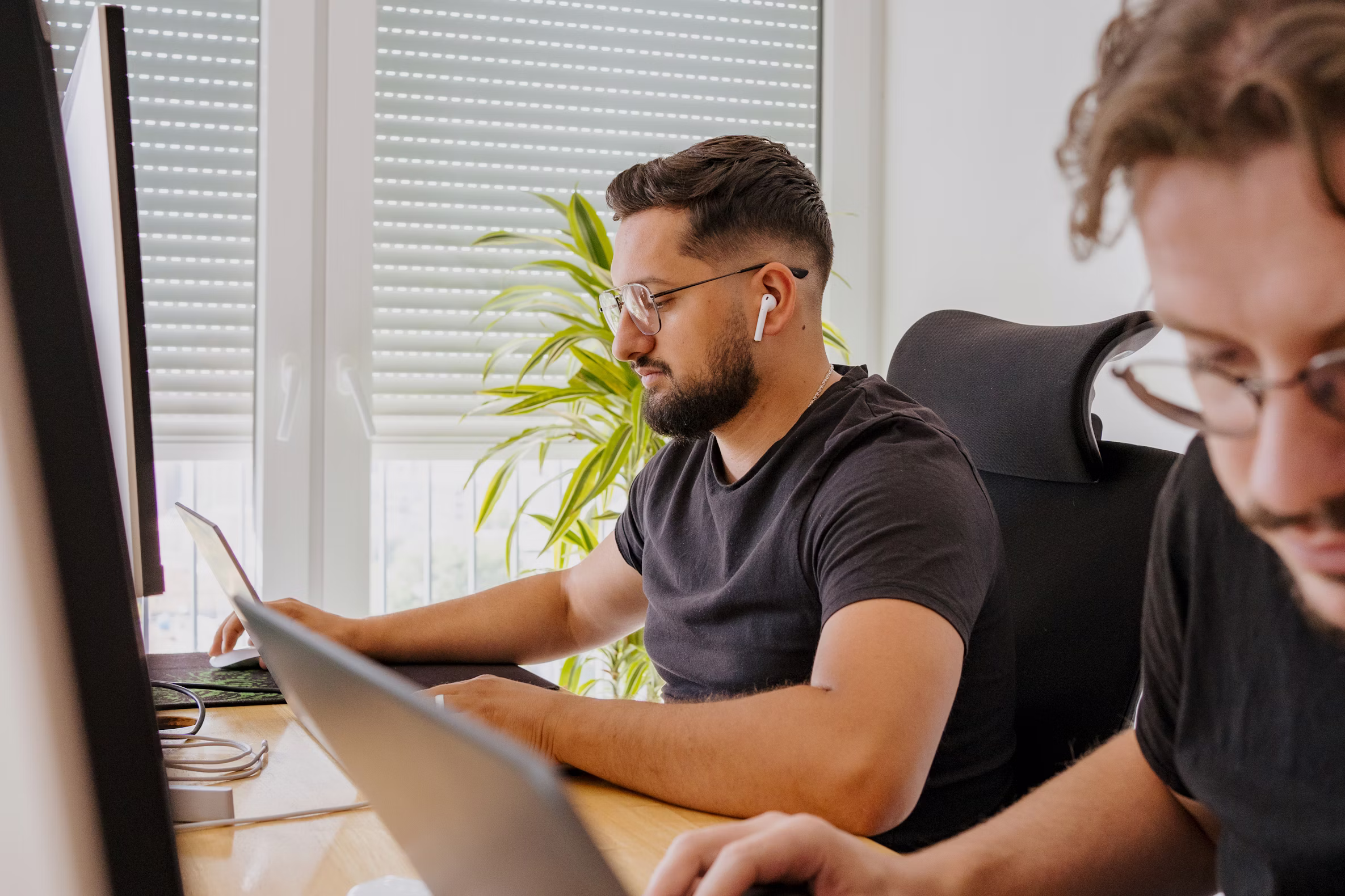 Two members of the Tarea team working at their desks in a quiet office.